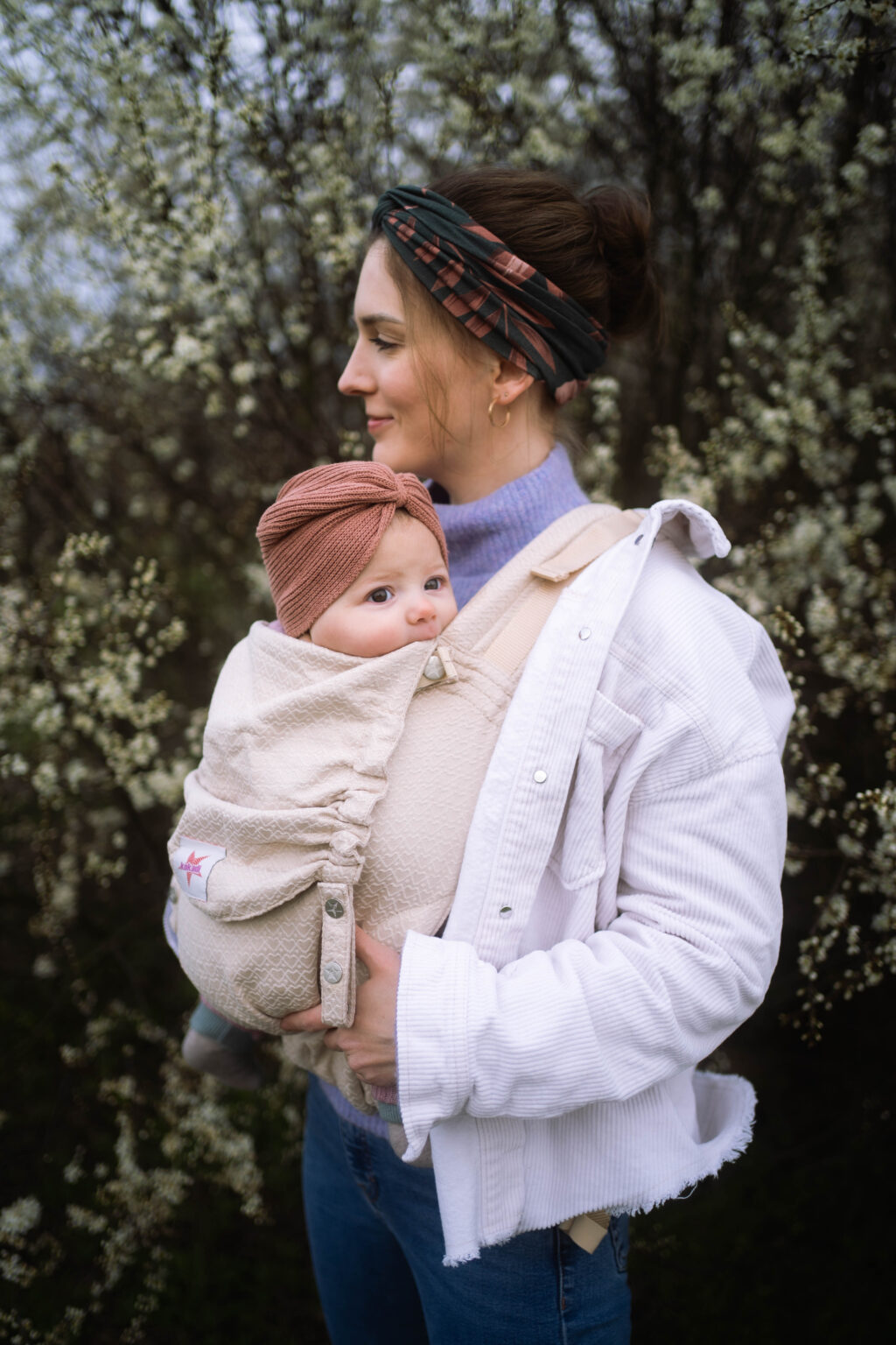 Galerie Eine junge Mama mit einem kleinen Baby im Arm in der Natur bei einem Familienshoot