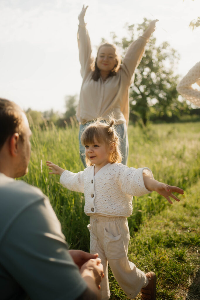 Tocher läuft in Arme vom Vater Mutter im Hintergrund lacht