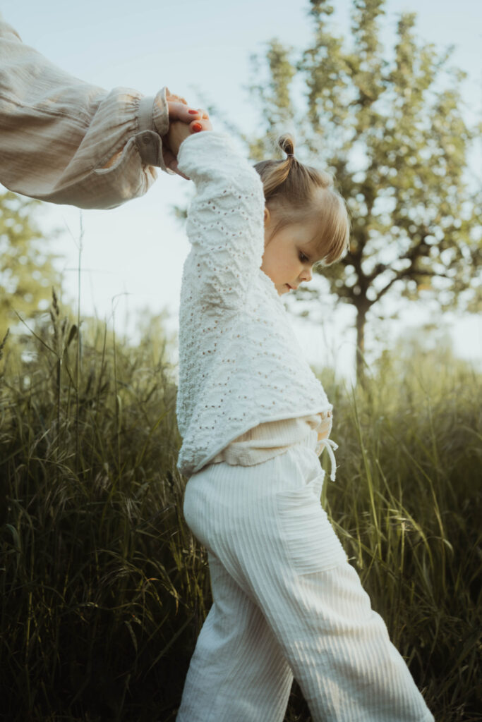 Kleine Tochter läuft an Hand der Mutter durch Natur Familienfotografie in Berlin & Brandenburg