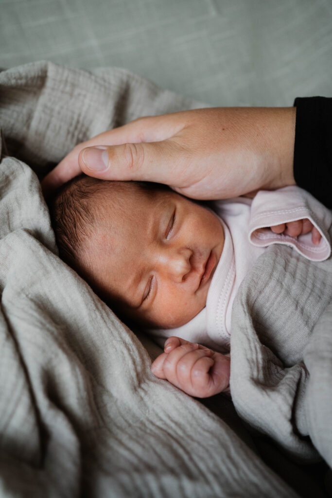 Baby eine Woche alt mit Hand der Mutter auf dem Kopf Familienfotografie in Berlin