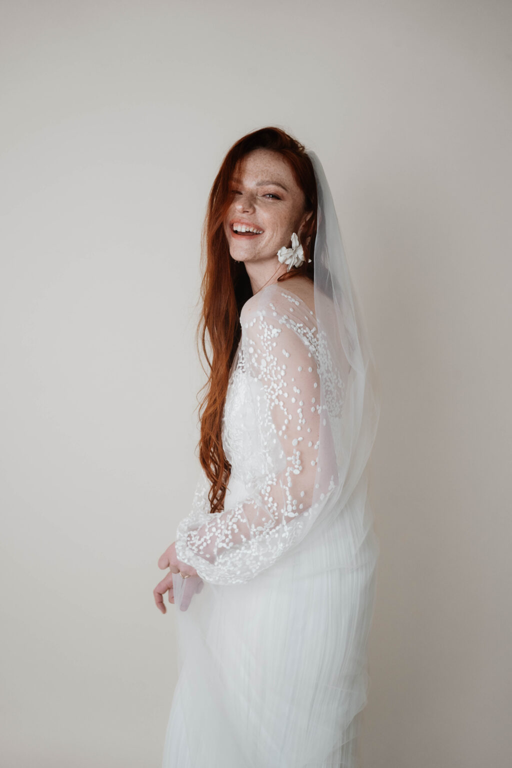 Braut im weißen Hochzeitskleid lachend mit roten Haaren Hochzeitsfotografie in Berlin