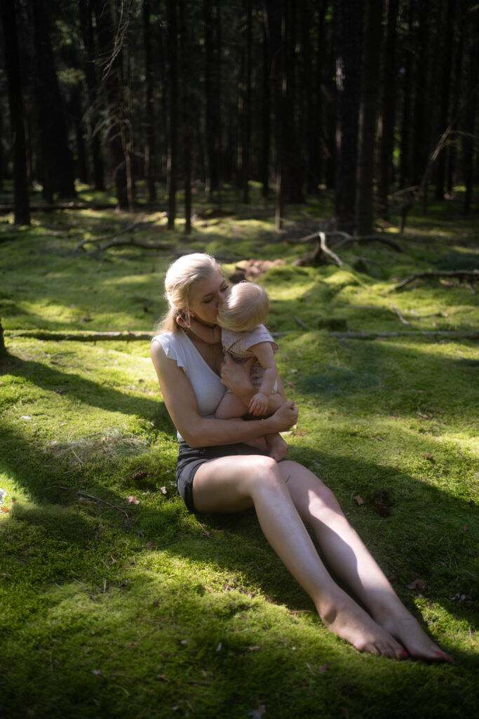 Mama mit ihrem Baby im Wald sitzend auf Moos