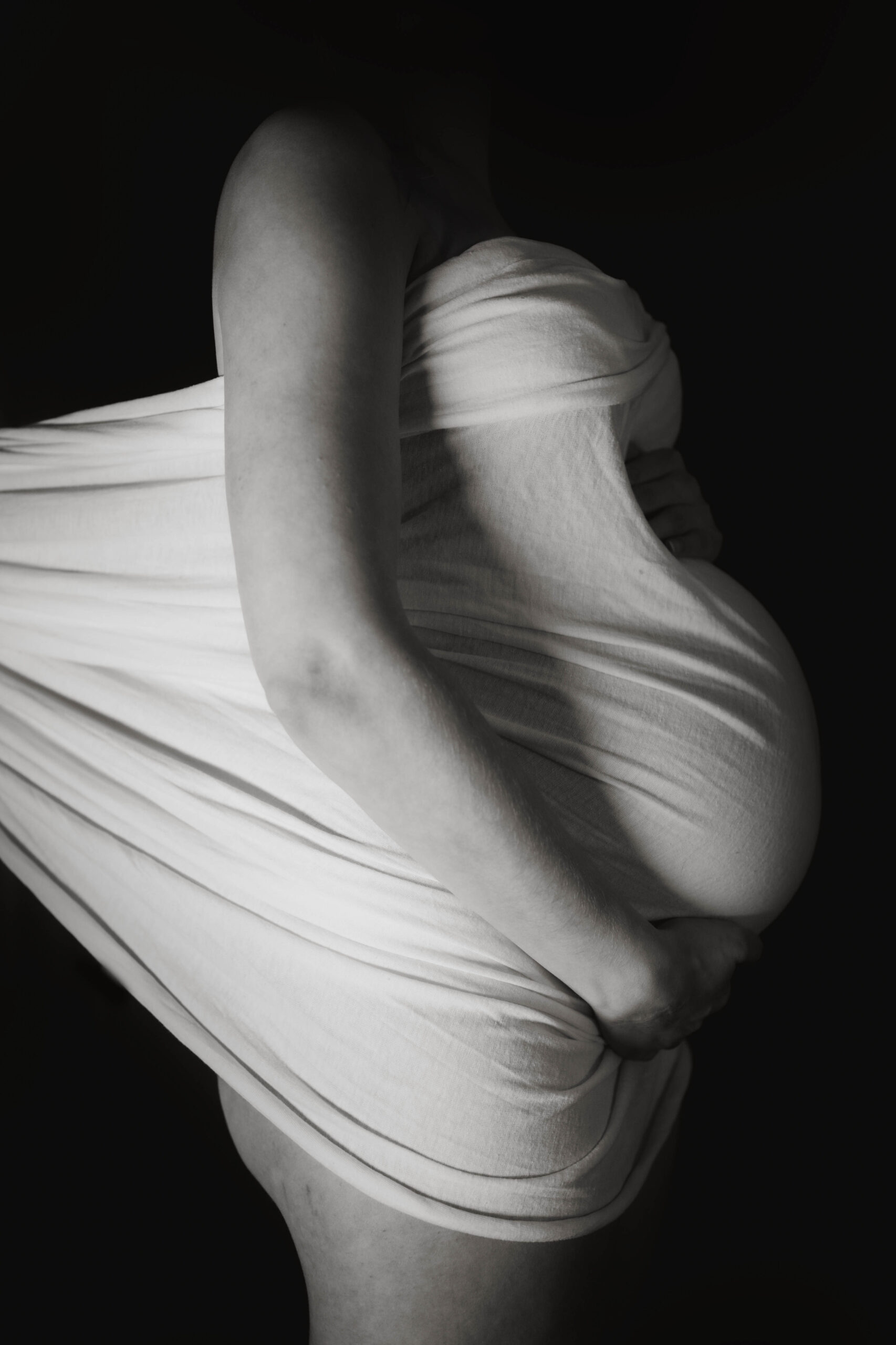 Babybauch eingehüllt in weißen Stoff