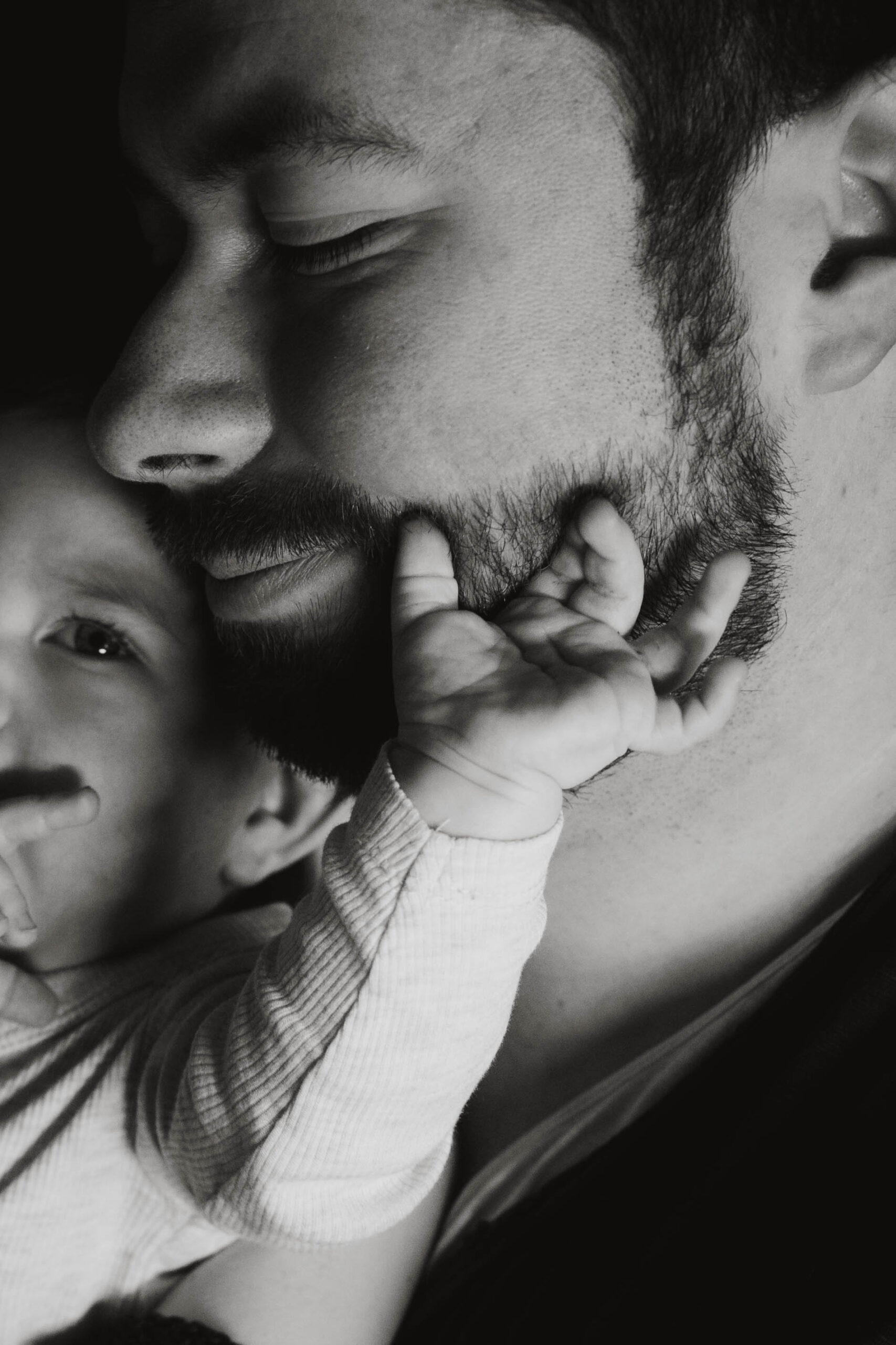 Baby lässt mit kleiner Hand in Gesicht von Papa