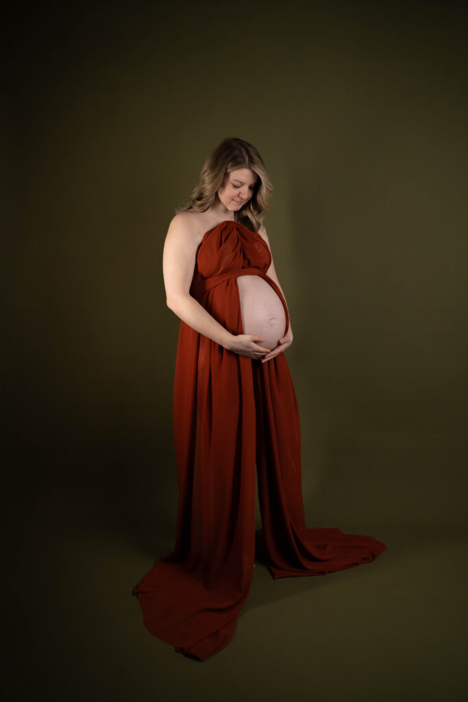 schwangere Frau im Studio mit rotem langem Kleid