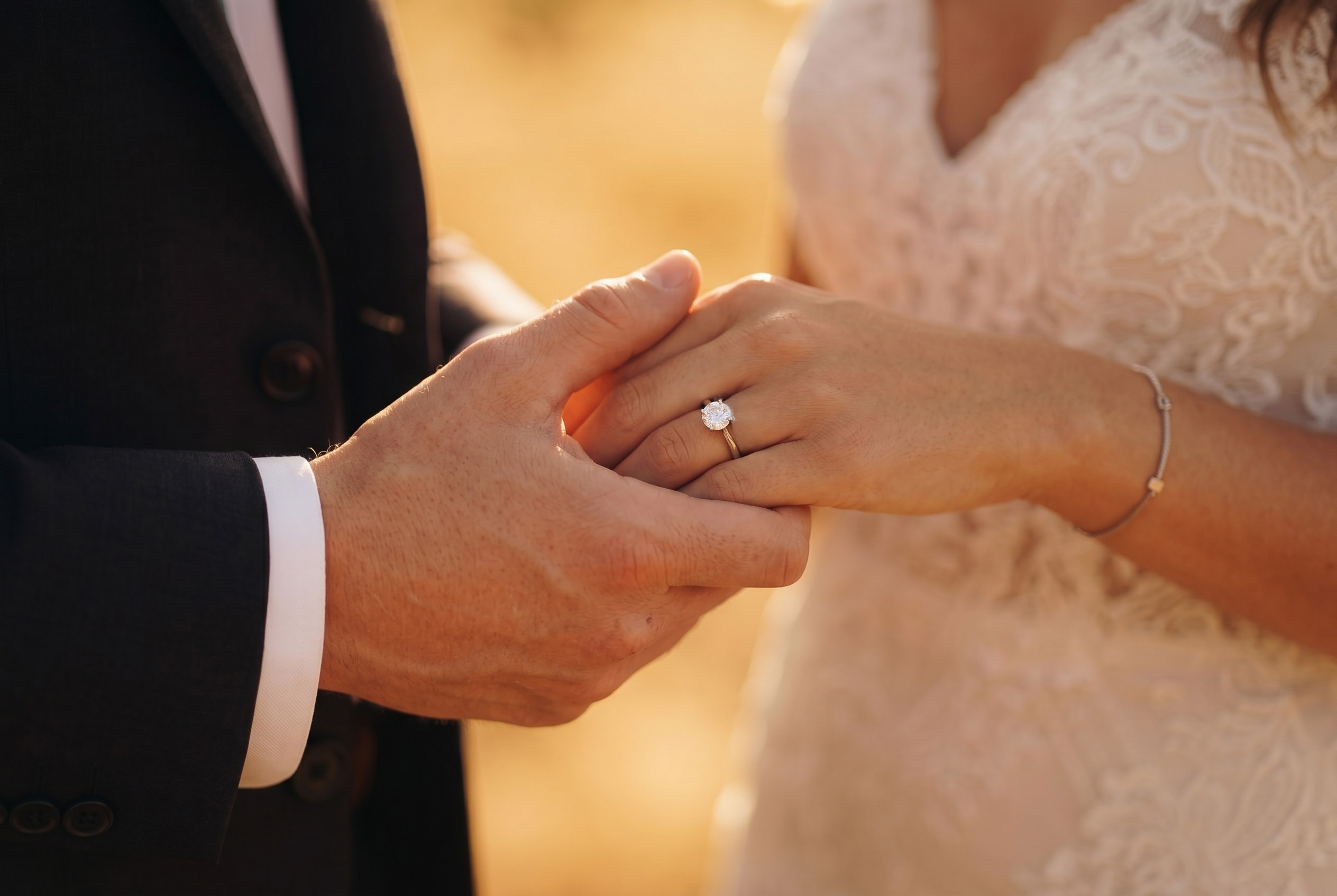 Hochzeitspaar hält Hände und zeigt Ehering