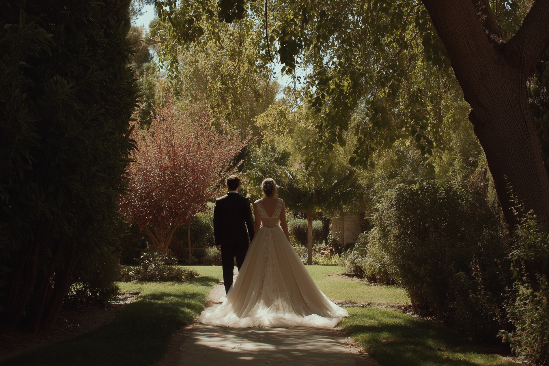 Paar in Hochzeitskleid und Sakko steht im Garten