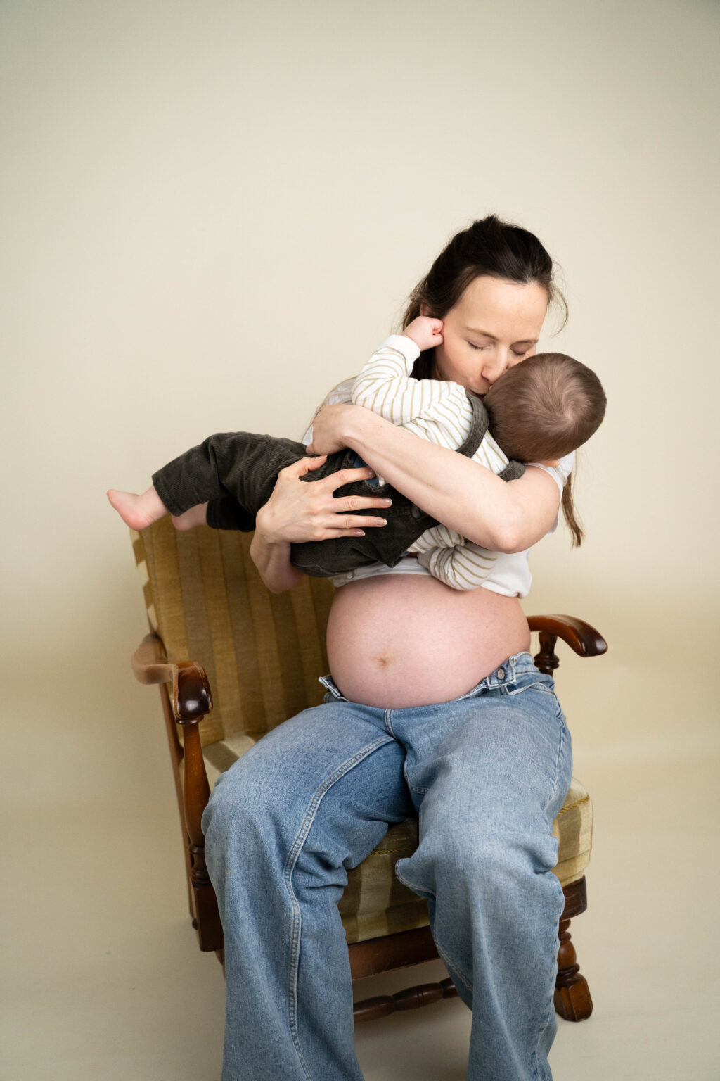 junge Frau mit Babybauch und Kleinkind auf dem Arm