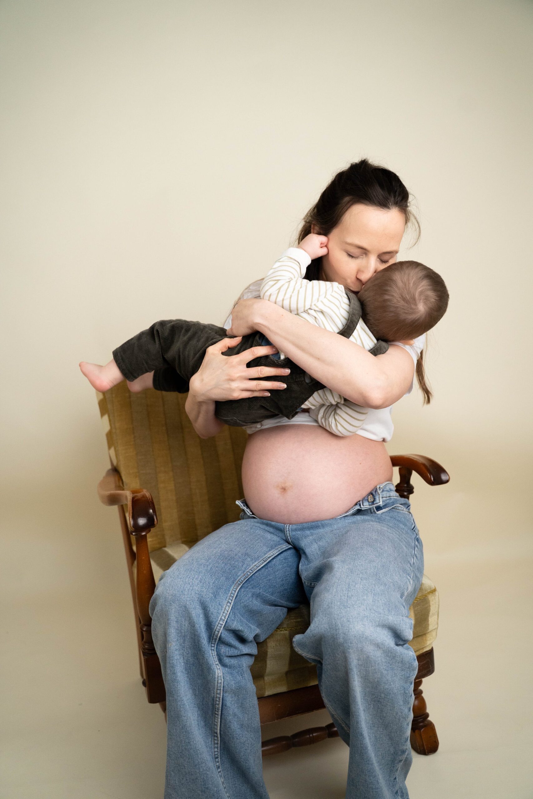 junge Frau mit Babybauch und Kleinkind auf dem Arm