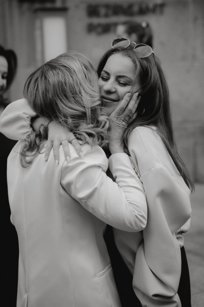 Mutter und Tochter umarmen sich bei Gratulation einer Hochzeit